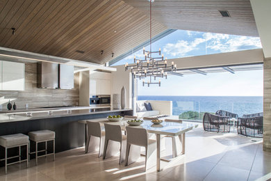 Huge minimalist single-wall marble floor and beige floor eat-in kitchen photo in San Diego with an undermount sink, flat-panel cabinets, white cabinets, solid surface countertops, beige backsplash, slate backsplash, stainless steel appliances, an island and gray countertops