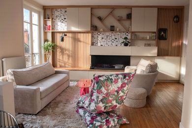 Modelo de biblioteca en casa abierta tradicional renovada pequeña con paredes beige, suelo de madera en tonos medios y chimenea de doble cara