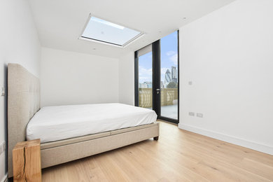 This is an example of a mid-sized contemporary bedroom in London with light hardwood floors.