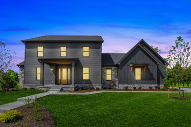 Photo of a mid-sized country two-storey black house exterior in Columbus with concrete fiberboard siding, a shingle roof, a black roof and board and batten siding.