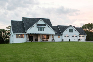 Large cottage white two-story mixed siding house exterior idea in Other with a hip roof and a shingle roof