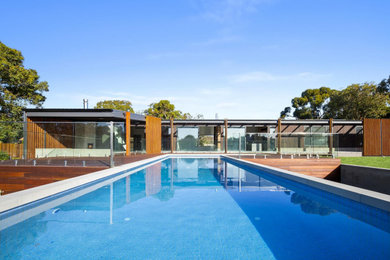 Expansive contemporary backyard rectangular pool in Geelong with a pool house and concrete pavers.