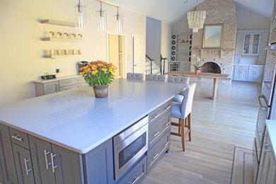 This is an example of an expansive arts and crafts eat-in kitchen in Providence with a single-bowl sink, shaker cabinets, grey cabinets, quartzite benchtops, grey splashback, stone tile splashback, stainless steel appliances and light hardwood floors.