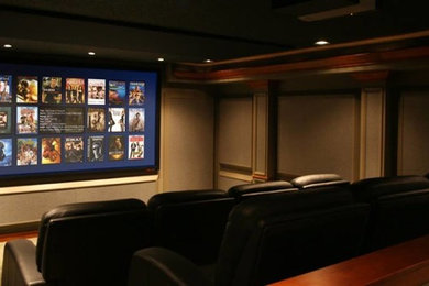 This is an example of a large modern enclosed home theatre in Cleveland with brown walls, carpet and a projector screen.