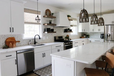Large contemporary l-shaped kitchen/diner in Baltimore with a single-bowl sink, shaker cabinets, white cabinets, engineered stone countertops, white splashback, marble splashback, stainless steel appliances, medium hardwood flooring, an island, brown floors and white worktops.