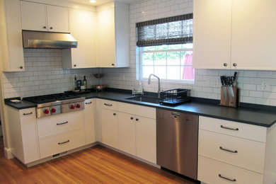 Eat-in kitchen - mid-sized transitional u-shaped medium tone wood floor and brown floor eat-in kitchen idea in Boston with a single-bowl sink, shaker cabinets, white cabinets, quartzite countertops, white backsplash, subway tile backsplash, stainless steel appliances, a peninsula and black countertops