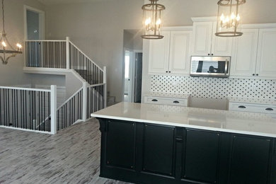 Mid-sized transitional l-shaped vinyl floor open concept kitchen photo in Calgary with raised-panel cabinets, white backsplash, ceramic backsplash, an island, an undermount sink, white cabinets, quartz countertops and stainless steel appliances
