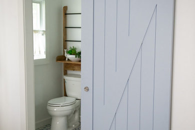 Alcove shower - small coastal 3/4 cement tile floor and multicolored floor alcove shower idea in New York with furniture-like cabinets, white cabinets, a two-piece toilet, white walls, an undermount sink, quartz countertops, a hinged shower door and white countertops