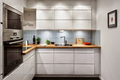 Ejemplo de cocinas en L blanca y madera tropical pequeña cerrada sin isla con fregadero sobremueble, armarios con paneles lisos, puertas de armario blancas, encimera de madera, electrodomésticos de acero inoxidable, suelo de baldosas de cerámica, suelo negro y encimeras marrones