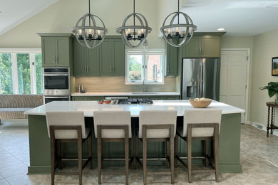 Expansive transitional kitchen in DC Metro with an undermount sink, shaker cabinets, green cabinets, quartz benchtops, beige splashback, glass tile splashback, stainless steel appliances, limestone floors, with island, multi-coloured floor, white benchtop and vaulted.