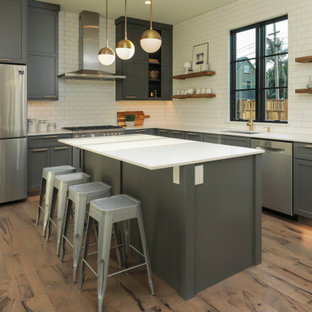 Modelo de cocina comedor en L y bandeja, clásica renovada, de tamaño medio, con fregadero encastrado, armarios con paneles empotrados, puertas de armario grises, encimera de cuarzo compacto, salpicadero blanco, salpicadero de azulejos tipo metro, electrodomésticos de acero inoxidable, suelo de madera clara, una isla, suelo multicolor y encimeras blancas