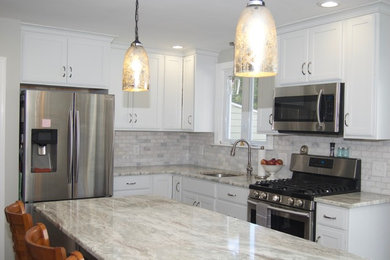 This is an example of a mid-sized transitional l-shaped kitchen in Philadelphia with a single-bowl sink, shaker cabinets, white cabinets, quartzite benchtops, grey splashback, stone tile splashback, stainless steel appliances, with island and dark hardwood floors.