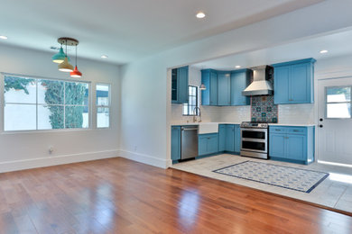 Example of a mid-sized transitional l-shaped ceramic tile and multicolored floor eat-in kitchen design in Los Angeles with a drop-in sink, blue cabinets, multicolored backsplash, ceramic backsplash, stainless steel appliances, no island and white countertops