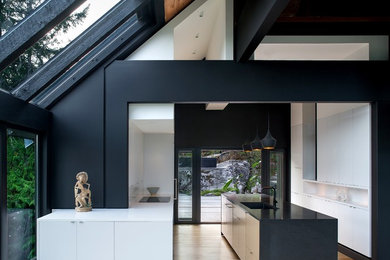 Example of a minimalist kitchen design in Vancouver with flat-panel cabinets and an island