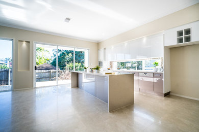Photo of a mid-sized modern single-wall separate kitchen in Brisbane with a drop-in sink, raised-panel cabinets, white cabinets, limestone benchtops, brown splashback, brick splashback, coloured appliances, cement tiles, with island and grey floor.