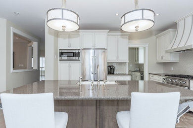 Design ideas for a large transitional kitchen in Toronto with a farmhouse sink, white cabinets, quartz benchtops, grey splashback, ceramic splashback, stainless steel appliances and with island.