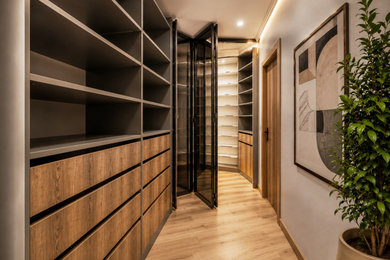Design ideas for a medium sized contemporary built-in wardrobe in Oxfordshire with flat-panel cabinets, medium wood cabinets, light hardwood flooring, brown floors, a drop ceiling and feature lighting.