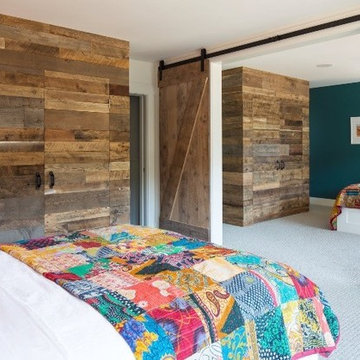 Reclaimed Wood Paneling and Barn Doors in a Rustic Farmhouse Bedroom
