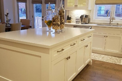 Open concept kitchen - mid-sized transitional l-shaped medium tone wood floor and brown floor open concept kitchen idea in Toronto with an undermount sink, beaded inset cabinets, white cabinets, solid surface countertops, white backsplash, brick backsplash, stainless steel appliances, an island and white countertops