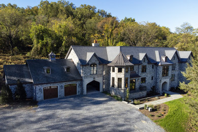 Large elegant gray two-story stone house exterior photo in Other with a mixed material roof