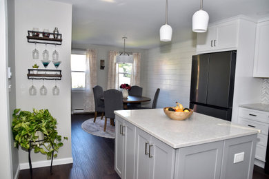 Example of a mid-sized mid-century modern l-shaped laminate floor and brown floor eat-in kitchen design in Bridgeport with a single-bowl sink, shaker cabinets, white cabinets, quartz countertops, gray backsplash, subway tile backsplash, stainless steel appliances, an island and gray countertops