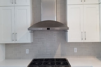 Mid-sized transitional open concept kitchen photo in Jacksonville with shaker cabinets, white cabinets, quartz countertops, gray backsplash, subway tile backsplash, stainless steel appliances and white countertops