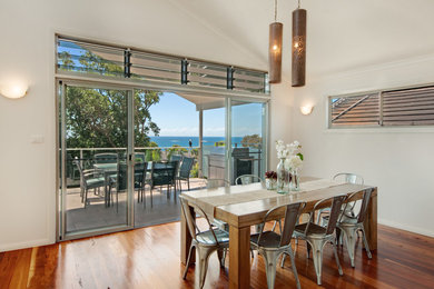 Photo of a beach style open plan dining in Central Coast with white walls and medium hardwood floors.