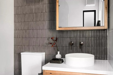 Inspiration for a small modern 3/4 black tile and subway tile terrazzo floor, gray floor and single-sink bathroom remodel in Los Angeles with shaker cabinets, medium tone wood cabinets, a one-piece toilet, black walls, a vessel sink, quartz countertops, white countertops, a niche and a floating vanity