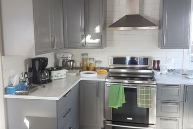 Inspiration for a mid-sized transitional l-shaped medium tone wood floor and brown floor kitchen remodel in Calgary with raised-panel cabinets, gray cabinets, quartz countertops, white backsplash, subway tile backsplash and stainless steel appliances