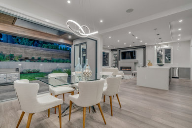 Trendy laminate floor and gray floor dining room photo in Vancouver with white walls and a standard fireplace