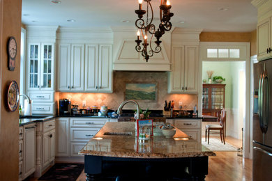 Eat-in kitchen - large traditional u-shaped medium tone wood floor eat-in kitchen idea in Boston with an undermount sink, raised-panel cabinets, white cabinets, granite countertops, beige backsplash, ceramic backsplash, stainless steel appliances and an island