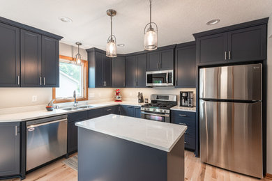 Inspiration for a large contemporary l-shaped kitchen in Minneapolis with an undermount sink, flat-panel cabinets, blue cabinets, quartz benchtops, ceramic splashback, stainless steel appliances, light hardwood floors, with island, white benchtop and white splashback.