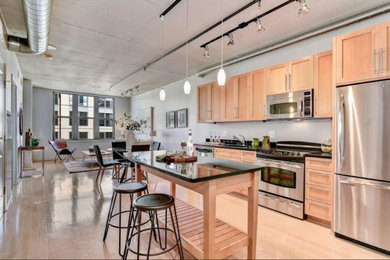 Inspiration for a mid-sized contemporary single-wall light wood floor and beige floor open concept kitchen remodel in DC Metro with an undermount sink, shaker cabinets, light wood cabinets, quartz countertops, gray backsplash, stainless steel appliances, an island and black countertops