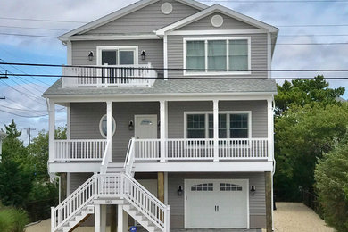 Inspiration for a large beach style two-storey grey house exterior in New York with vinyl siding, a gable roof and a shingle roof.