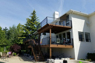 Example of a huge transitional backyard deck design in Other with a fire pit and a roof extension