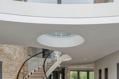 This is an example of a large contemporary wood curved staircase in Other with wood risers and wood railing.
