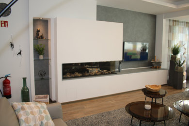 Imagen de salón abierto minimalista grande con chimenea lineal, marco de chimenea de piedra y pared multimedia