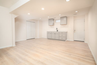 Example of a large classic walk-out vinyl floor and brown floor basement design in DC Metro with a bar and beige walls