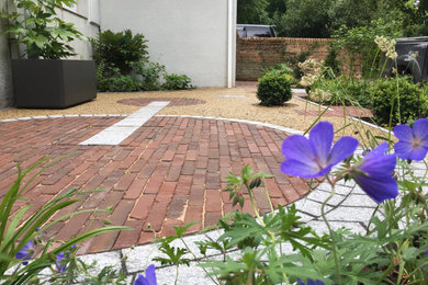 Photo of a small contemporary front xeriscape fully shaded garden for summer in Hampshire with brick paving.