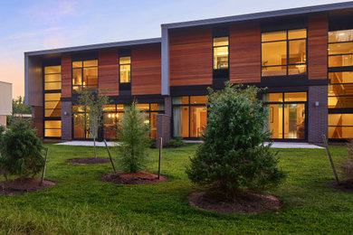Mid-sized minimalist brown two-story wood and clapboard exterior home photo in Other with a mixed material roof and a gray roof