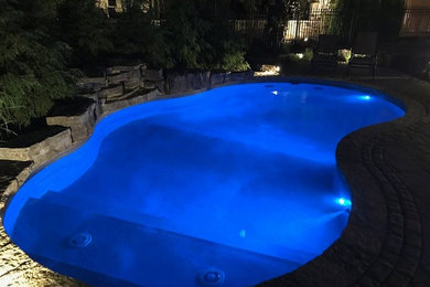 Inspiration for a large backyard custom-shaped pool in Toronto with concrete slab.