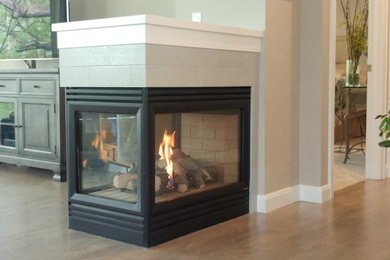 Inspiration for an open concept medium tone wood floor and gray floor living room remodel in Minneapolis with gray walls, a two-sided fireplace and a tile fireplace