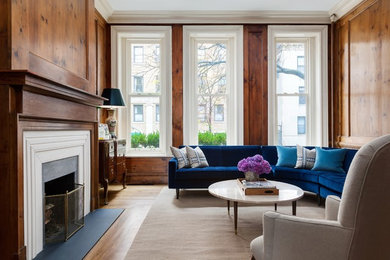Transitional enclosed medium tone wood floor and brown floor family room photo in New York with brown walls and a standard fireplace