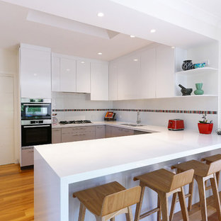 Inspiration for a mid-sized contemporary u-shaped kitchen pantry in Melbourne with a double-bowl sink, flat-panel cabinets, white cabinets, marble benchtops, white splashback, ceramic splashback, stainless steel appliances, medium hardwood floors, with island, yellow floor and white benchtop.