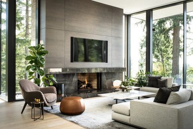 Photo of a large contemporary open plan living room in Vancouver with white walls, light hardwood flooring, a standard fireplace, a stone fireplace surround, a wall mounted tv and beige floors.
