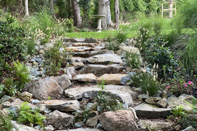Imagen de jardín en patio trasero con jardín francés, camino de entrada y adoquines de piedra natural
