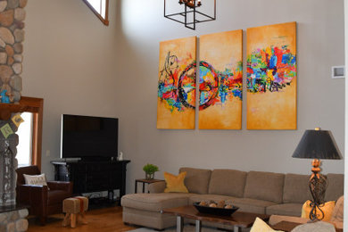 Modelo de sala de estar abierta moderna de tamaño medio con paredes beige, suelo de madera en tonos medios, estufa de leña, marco de chimenea de piedra, televisor independiente y suelo marrón