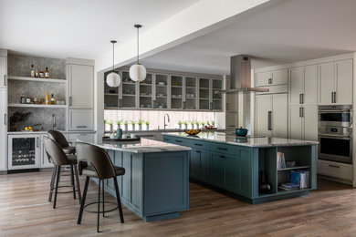 Inspiration for a transitional u-shaped dark wood floor and brown floor kitchen remodel in Seattle with an undermount sink, shaker cabinets, gray cabinets, window backsplash, stainless steel appliances, two islands and gray countertops