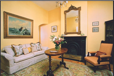 ブリスベンにある高級な中くらいなトラディショナルスタイルのおしゃれなリビング (黄色い壁、淡色無垢フローリング、標準型暖炉、金属の暖炉まわり、テレビなし) の写真
