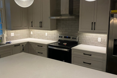 Large trendy l-shaped medium tone wood floor and brown floor eat-in kitchen photo in Atlanta with an undermount sink, shaker cabinets, gray cabinets, quartzite countertops, gray backsplash, porcelain backsplash, stainless steel appliances, an island and white countertops